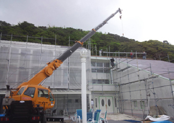 クレーン車を使い屋根材を運ぶ様子